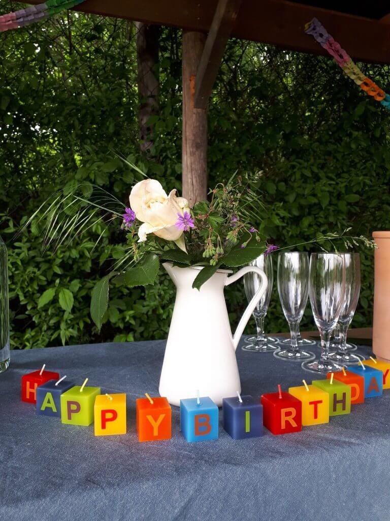 Hunde Geburtstagsparty. Blumenvase und Kerzen mit dem Schriftzug Happy Birthday auf dem gedeckten Tisch.