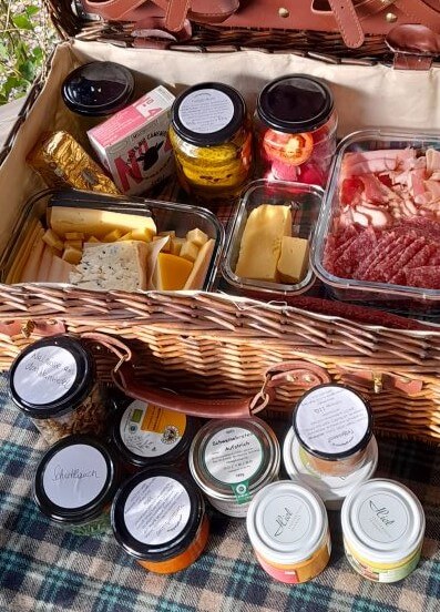 Hunde Picknick. Ein reich gefüllter Picknickkorb auf einer Picknickdecke.