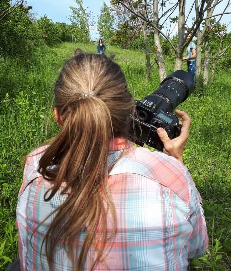 Hunde Fotoshooting. Man sieht die Fotografin von hinten, wie sie gerade Hunde fotografiert.