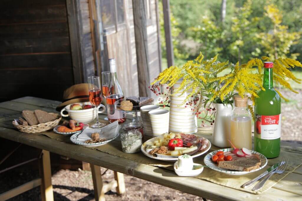 Weinviertler Picknick mit Hund. Reich gedeckter Holztisch mit Snacks und Getränken