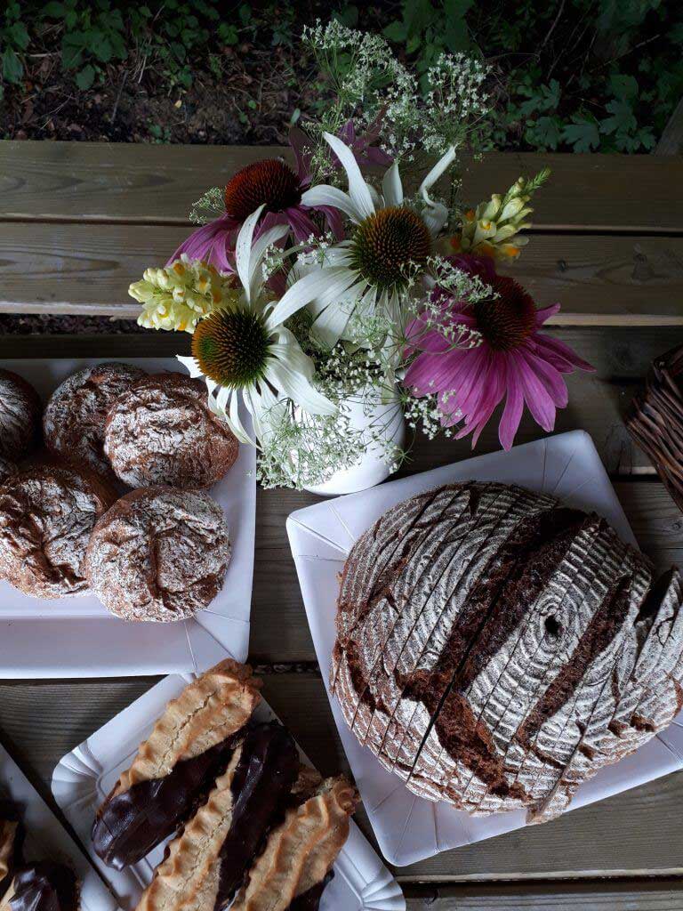Weinviertler Picknick. Gedeckter Holztisch mit Brot und Gebäck und einem Blumenstrauss